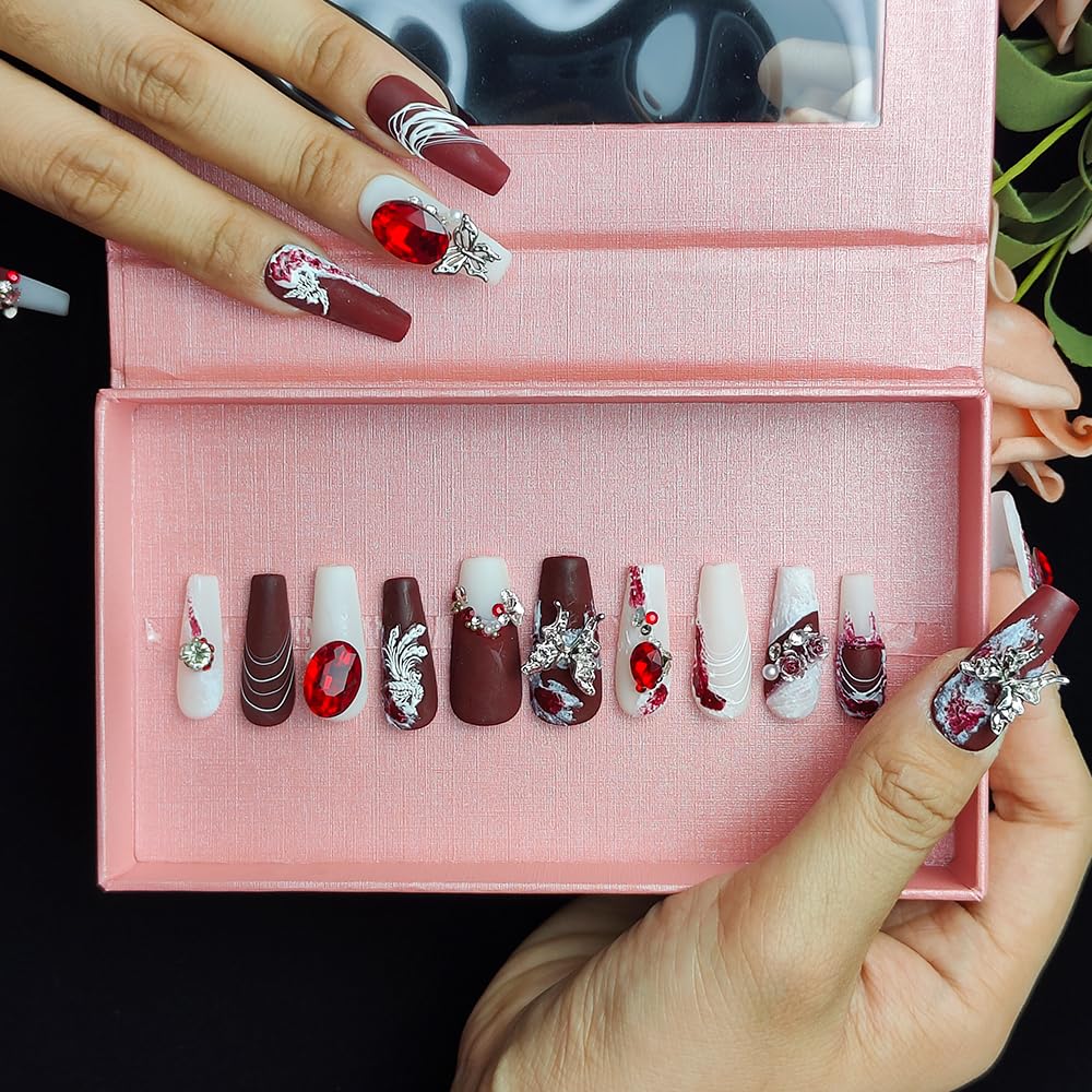 Long press-on nails set in open box, deep red and white with large red jewel accents