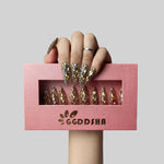 Almond press-on nails with gold and crystal rhinestone crown details, held in pink box
