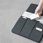 Black laptop bag sleeve close-up, open compartments with snap tabs and cable pocket