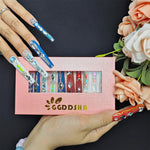 Long press-on nails in blue and teal with rhinestone trim, plus one red gem nail
