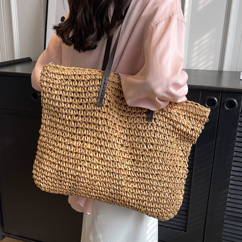 Woven shoulder beach bag in tan with black handles and adjustable shoulder strap
