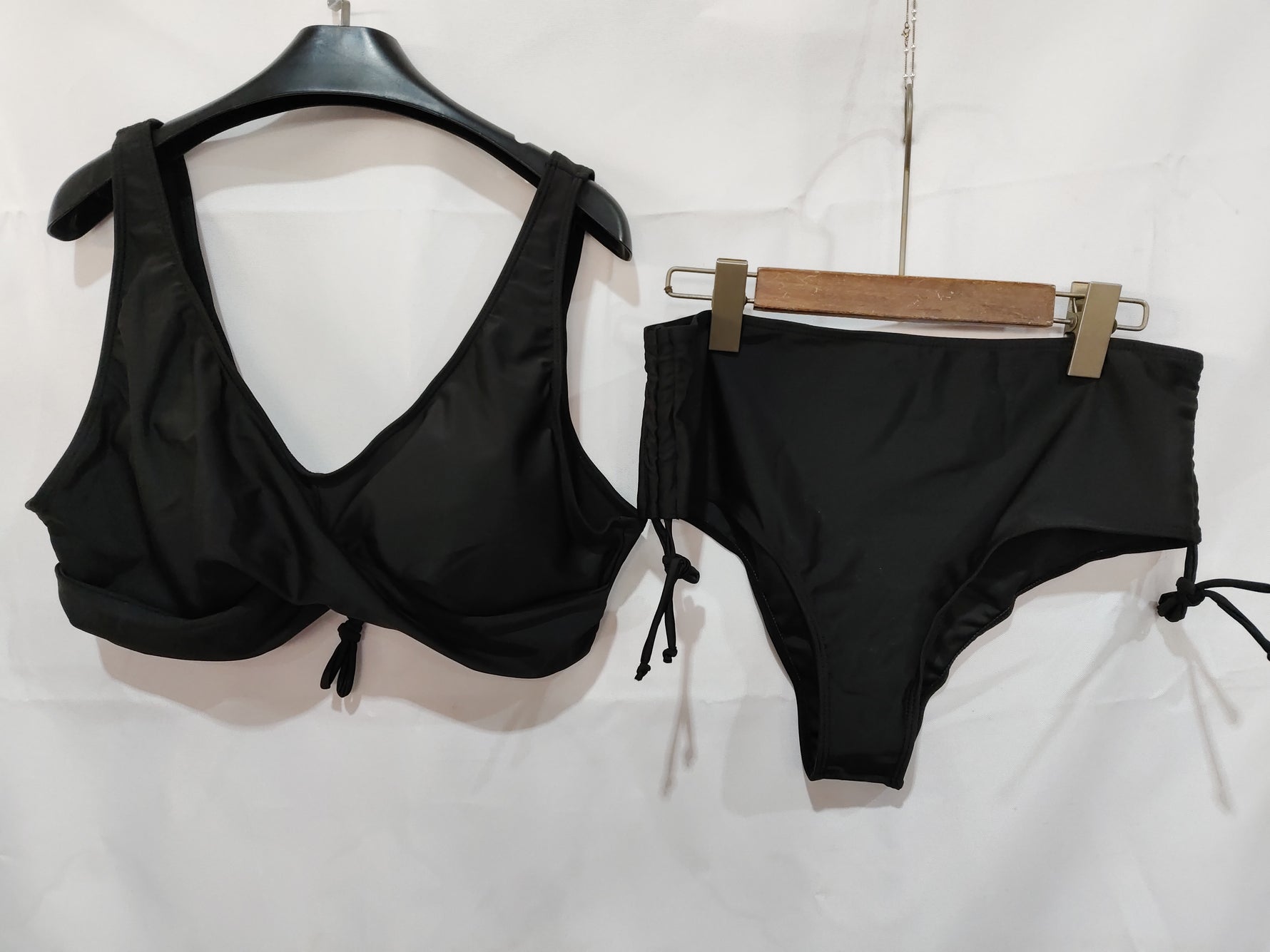 Black bikini bra top and high-waist drawstring bottoms on hangers