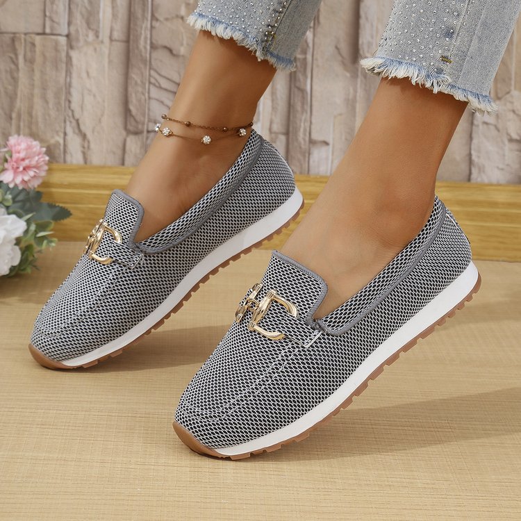 Dark women’s canvas flat sneakers with gold horsebit-style detail and white outsole.