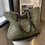 Woven shoulder beach bag in green with black handles and long curved strap