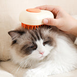 Cream electric pet grooming brush with orange bristle pins being used on a cat