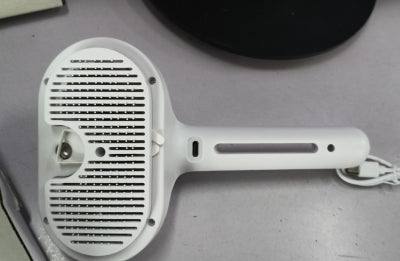 Close-up of white self-cleaning pet comb brush head with bristle teeth and slot openings