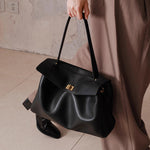 Black leather tote bag with short top handle, front flap and gold-tone clasp