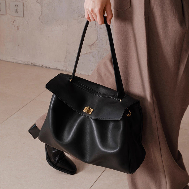 Black leather tote bag with short top handle, front flap and gold-tone clasp