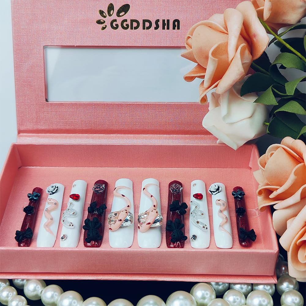 Long press-on nails set with white, red, and dark designs, bows, flowers, and rhinestones