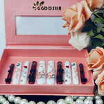 Long press-on nails set arranged in tray, white and dark red patterns with bows and rhinestones