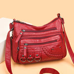 Red PU leather crossbody bag with layered zippers, braided front pocket, and 3 rings
