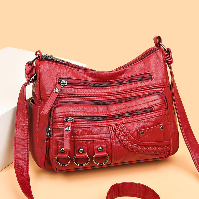 Red PU leather crossbody bag with layered zippers, braided front pocket, and 3 rings