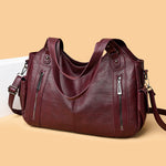 Burgundy PU handbag with top handles, shoulder strap, and front zip pockets