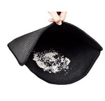 Black double-layer cat litter mat with folded flap and scattered litter on surface