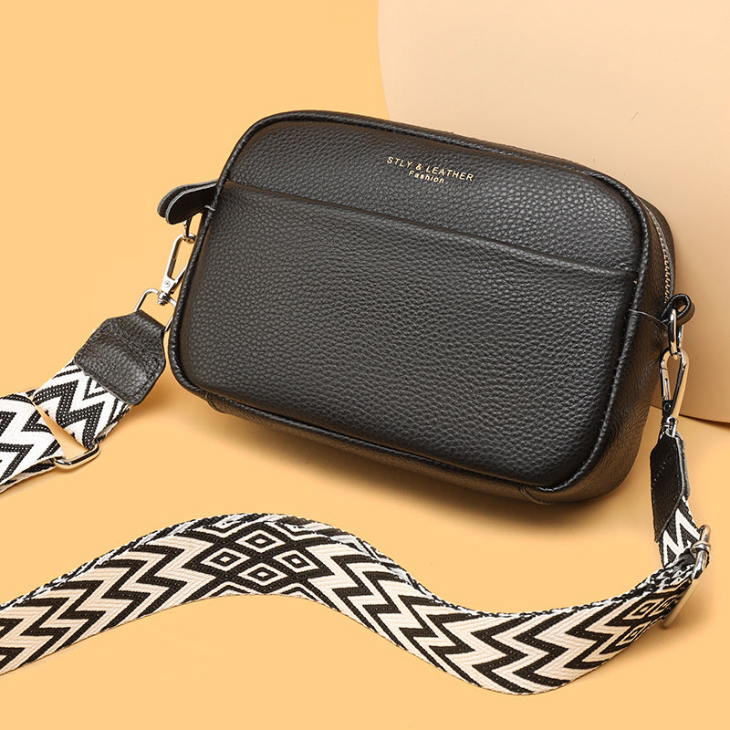 Genuine leather crossbody bag with black textured finish and patterned wide strap
