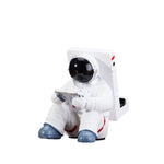 Astronaut phone holder resin figure with white suit and black helmet, holding a smartphone