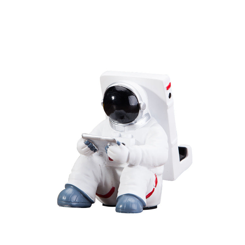 Astronaut phone holder resin figure with white suit and black helmet, holding a smartphone