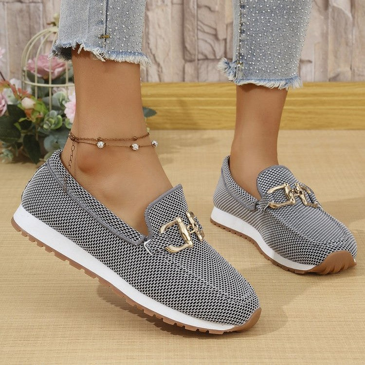 Dark women’s canvas flat sneakers with gold horsebit-style detail and white sole.