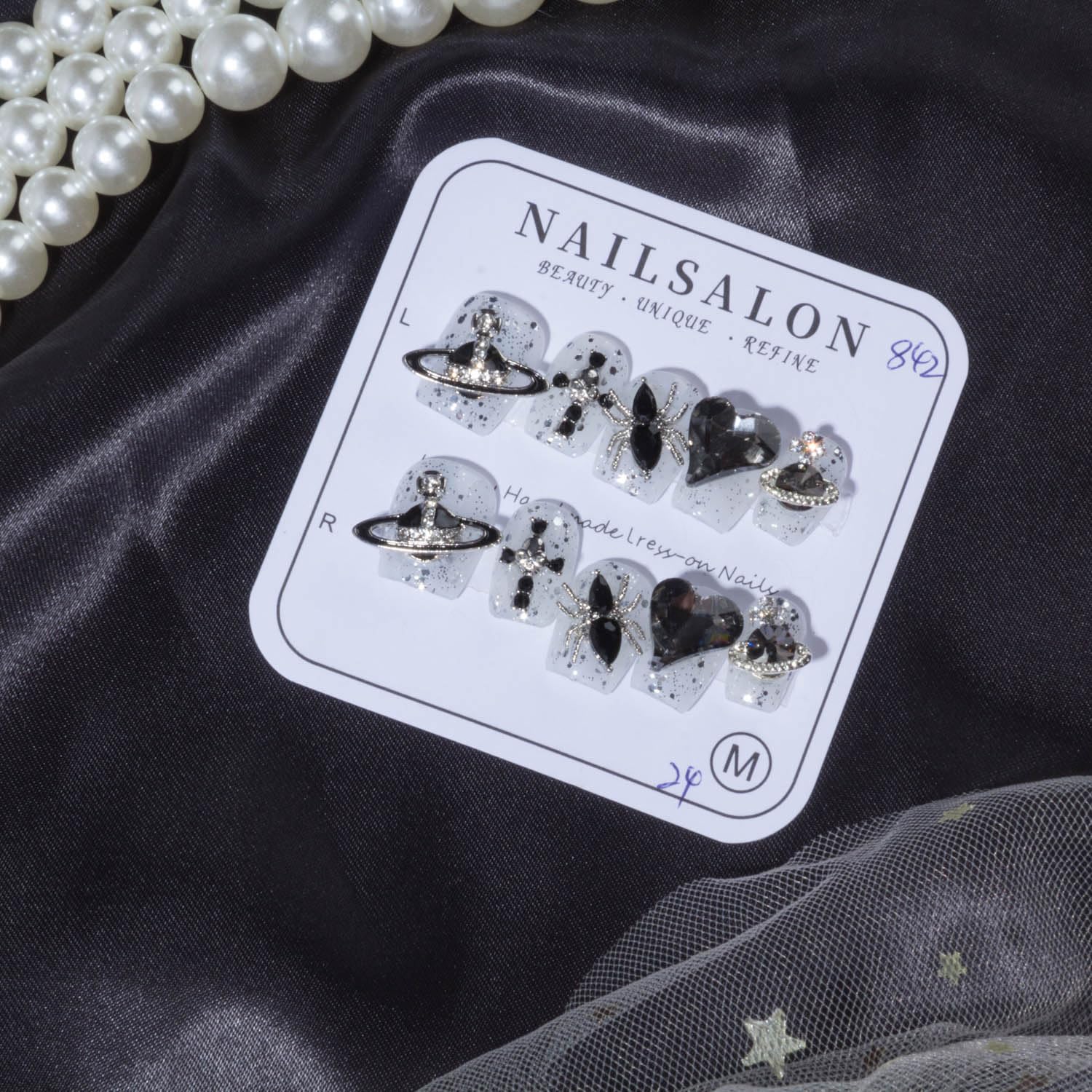 Short press-on nails set with silver glitter and black gemstone bow accents