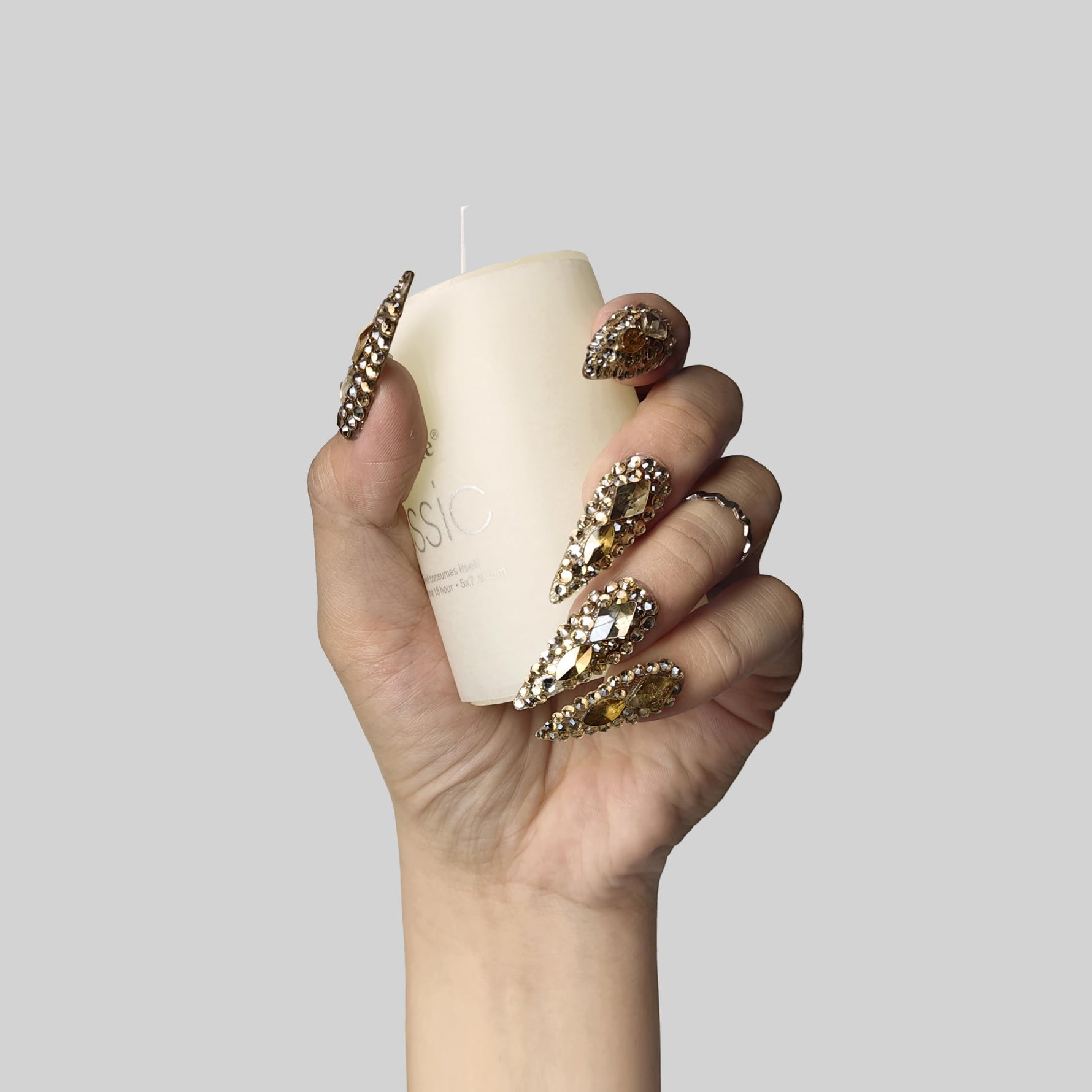 Almond press-on nails with gold and clear rhinestone crown motifs on fingertips
