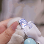 Pet LED nail grinder with clear LED shield, held near a pet paw