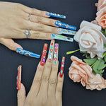Long press-on nails featuring blue rhinestone details, with red and green accent designs