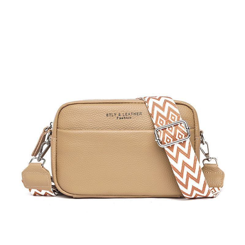 Beige small square leather crossbody bag with patterned strap, buckle detail, and zip top