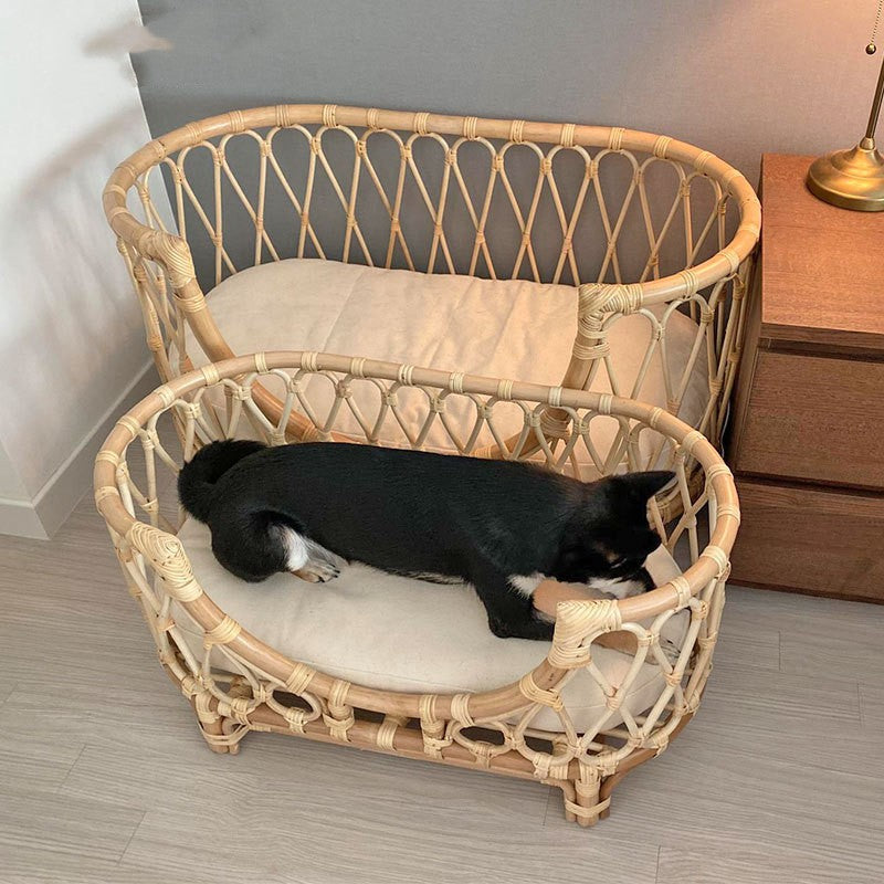 Handmade rattan pet bed with white liner cushion and dog curled up on top