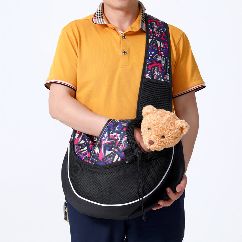 Black pet crossbody bag with graphic strap lining and front carrier opening, holding small pet