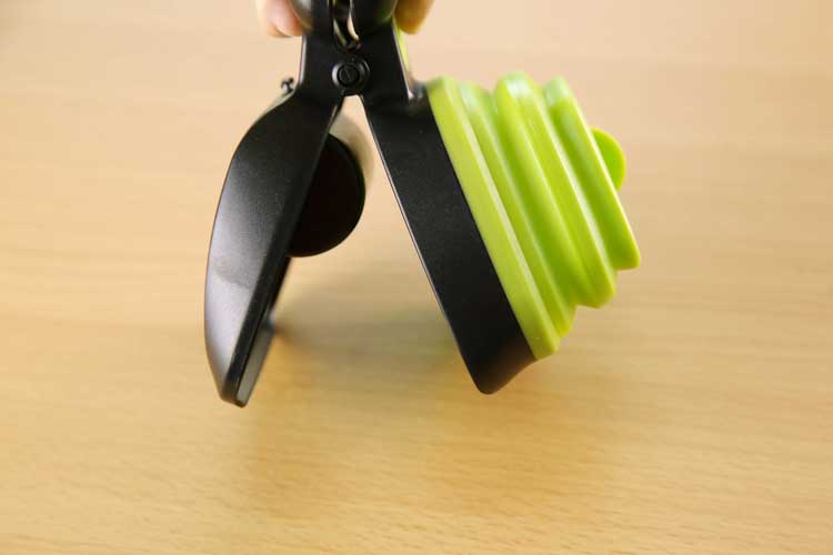 Foldable pet waste scooper with black grip and green folded scoop
