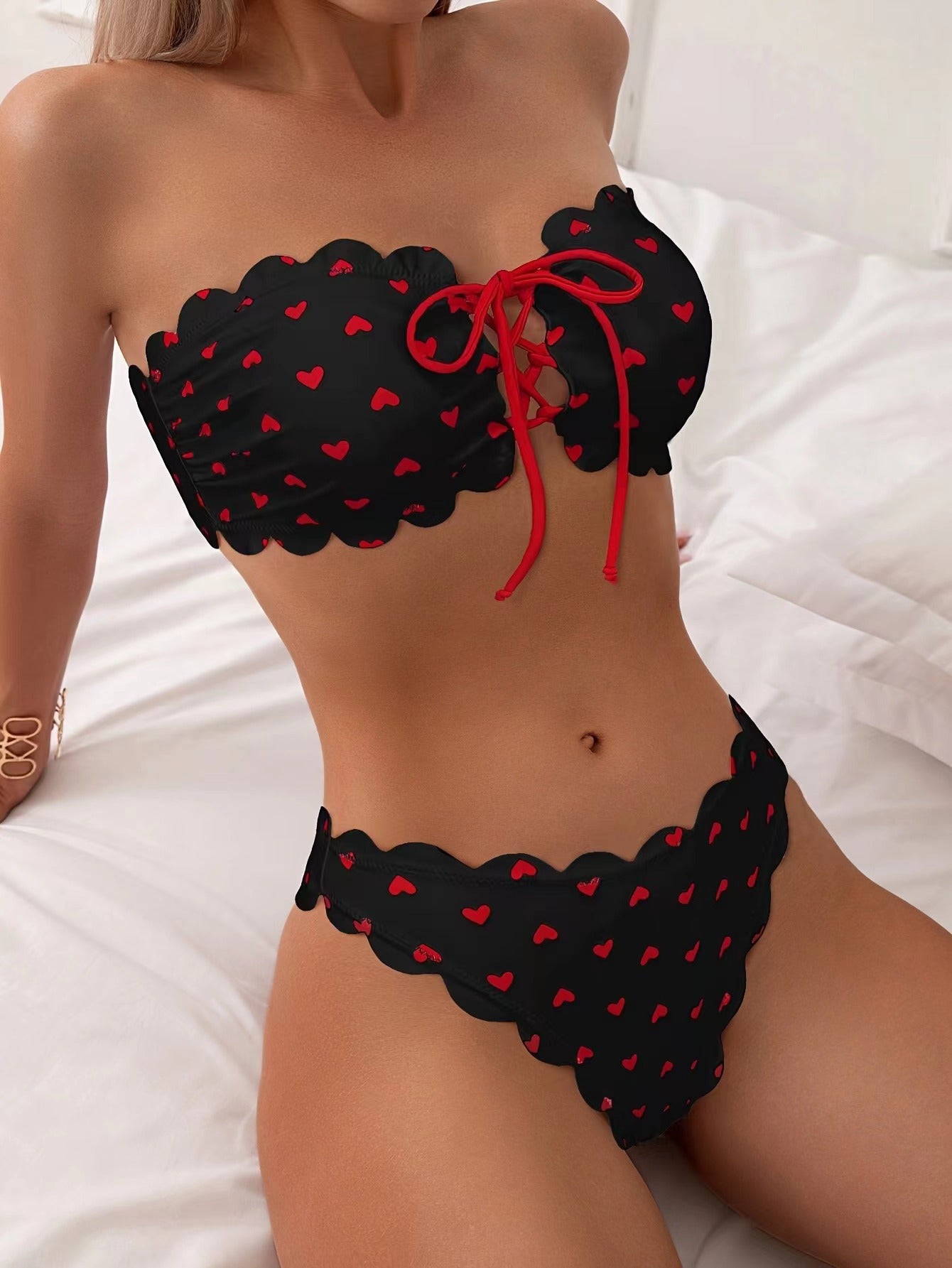 Black printed tube-top bikini with red hearts, red tie-front drawstring, scalloped high-waist briefs