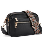 Black crossbody bag with floral embroidered strap and gold-tone hardware, front zip pocket