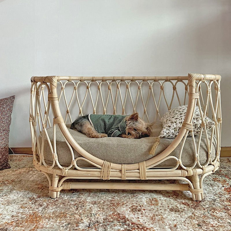 Handmade rattan pet bed with gray cushion, patterned pillows, white woven sides