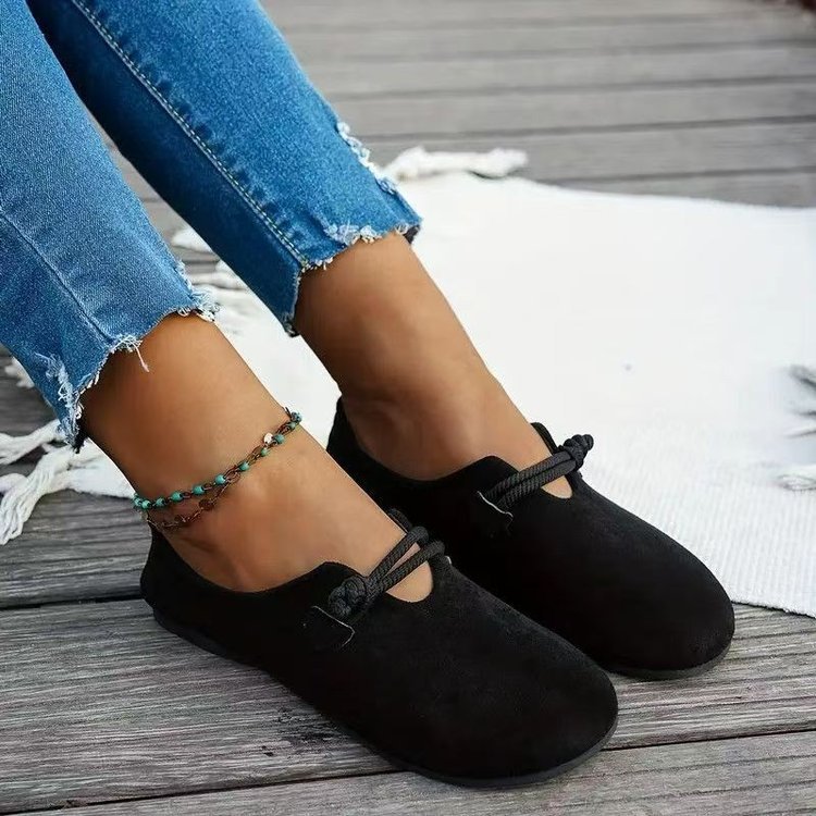 Black suede round-toe flat lace-up shoes on model with tied bow at vamp