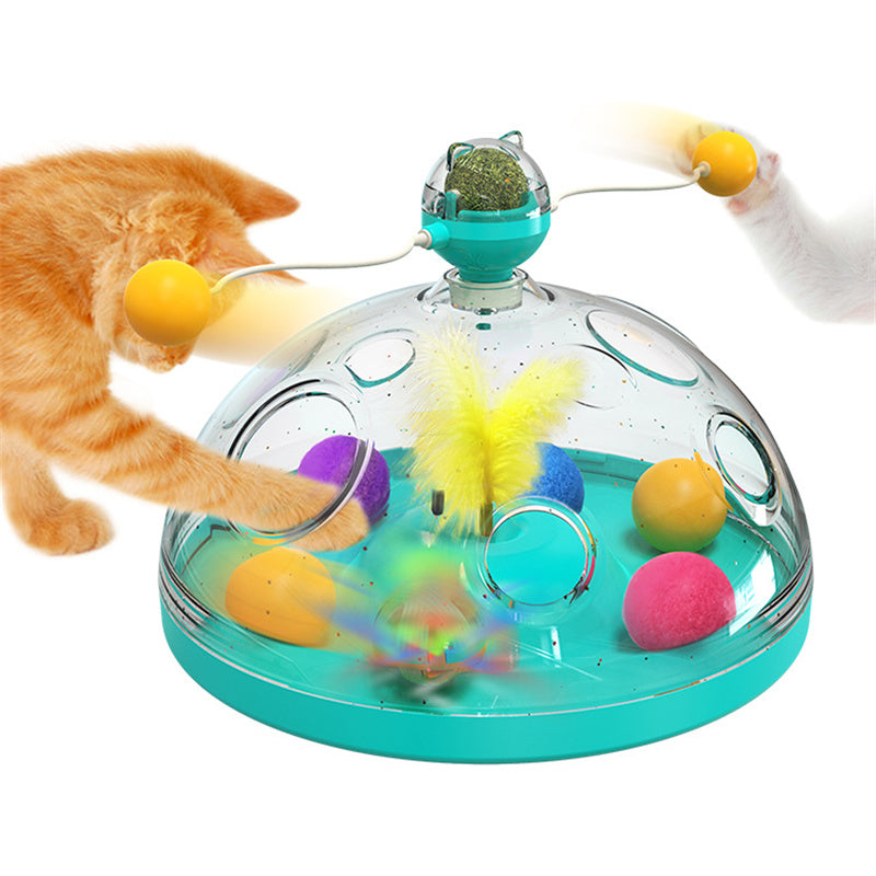 Interactive cat toy turntable with clear dome, teal base; tabby cat reaching for dangling balls