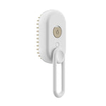 Electric steam pet brush with white body, beige power button, and comb bristles
