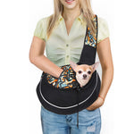 Black pet crossbody bag with colorful strap and front carrier opening, holding a small dog