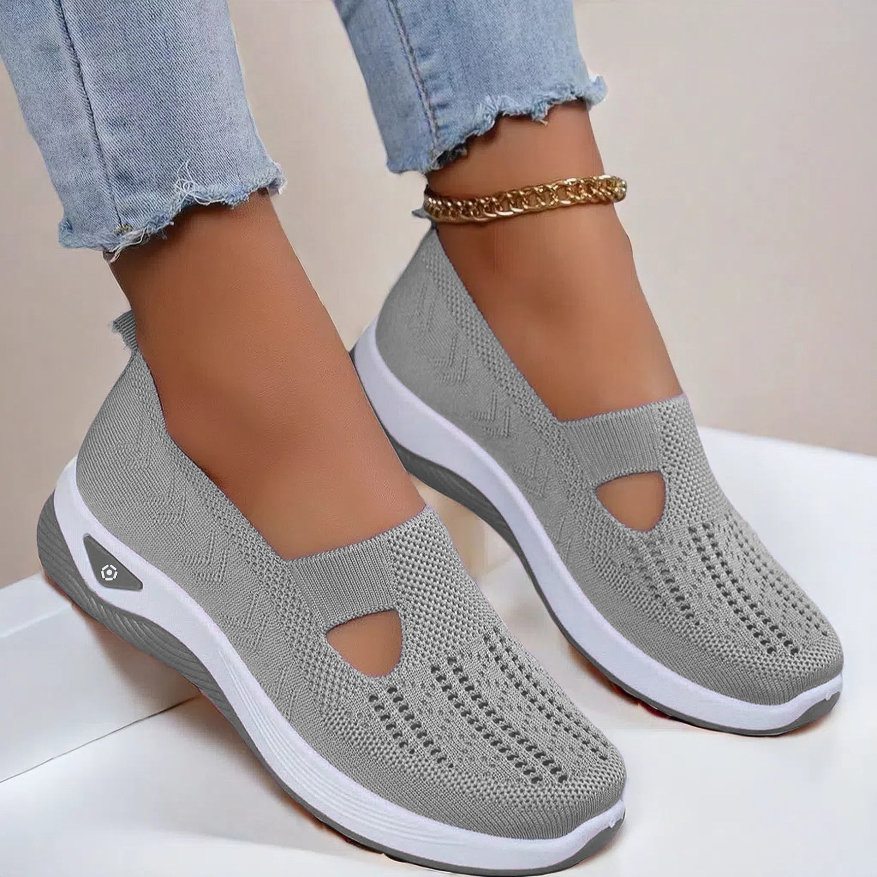 Light gray mesh slip-on flat shoes with oval cutouts and white cushioned soles