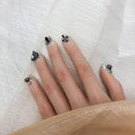 Short press-on nails with black gem bow and bead embellishments on silver glitter