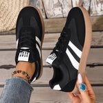Casual sneakers in black with white side stripes and tan rubber sole