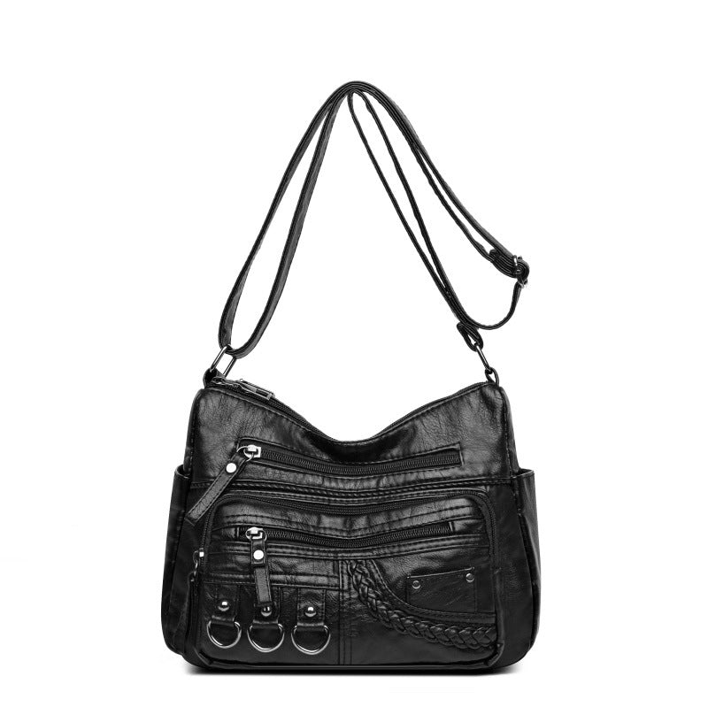 Black PU leather crossbody bag with top zipper, stacked front zip pockets, and braided detail