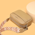 Genuine leather crossbody bag with beige body, top zipper, and patterned wide strap