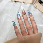 Short press on nails on fingers, nude pink base with blue glitter and gold accents