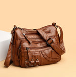 Brown PU leather crossbody bag with zippered front pockets and braided side panel