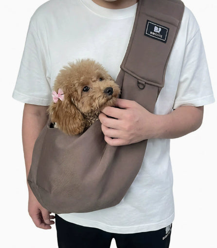 Brown pet shoulder carrier sling holding a small plush dog