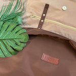 Brown Oxford cloth messenger bag with front leather-look logo patch and zipper pocket