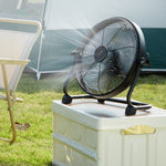 Black cordless floor fan on arched stand, placed on a cooler outdoors.