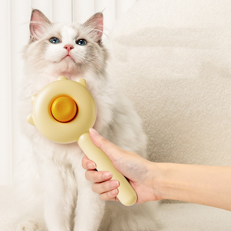 Cat grooming massage brush with yellow handle and orange button on round head