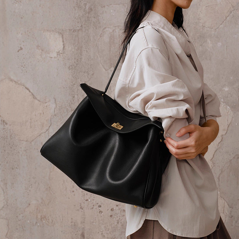Black leather tote bag with curved top handle and gold-tone clasp