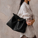 Black leather tote bag with curved top handle and gold-tone clasp